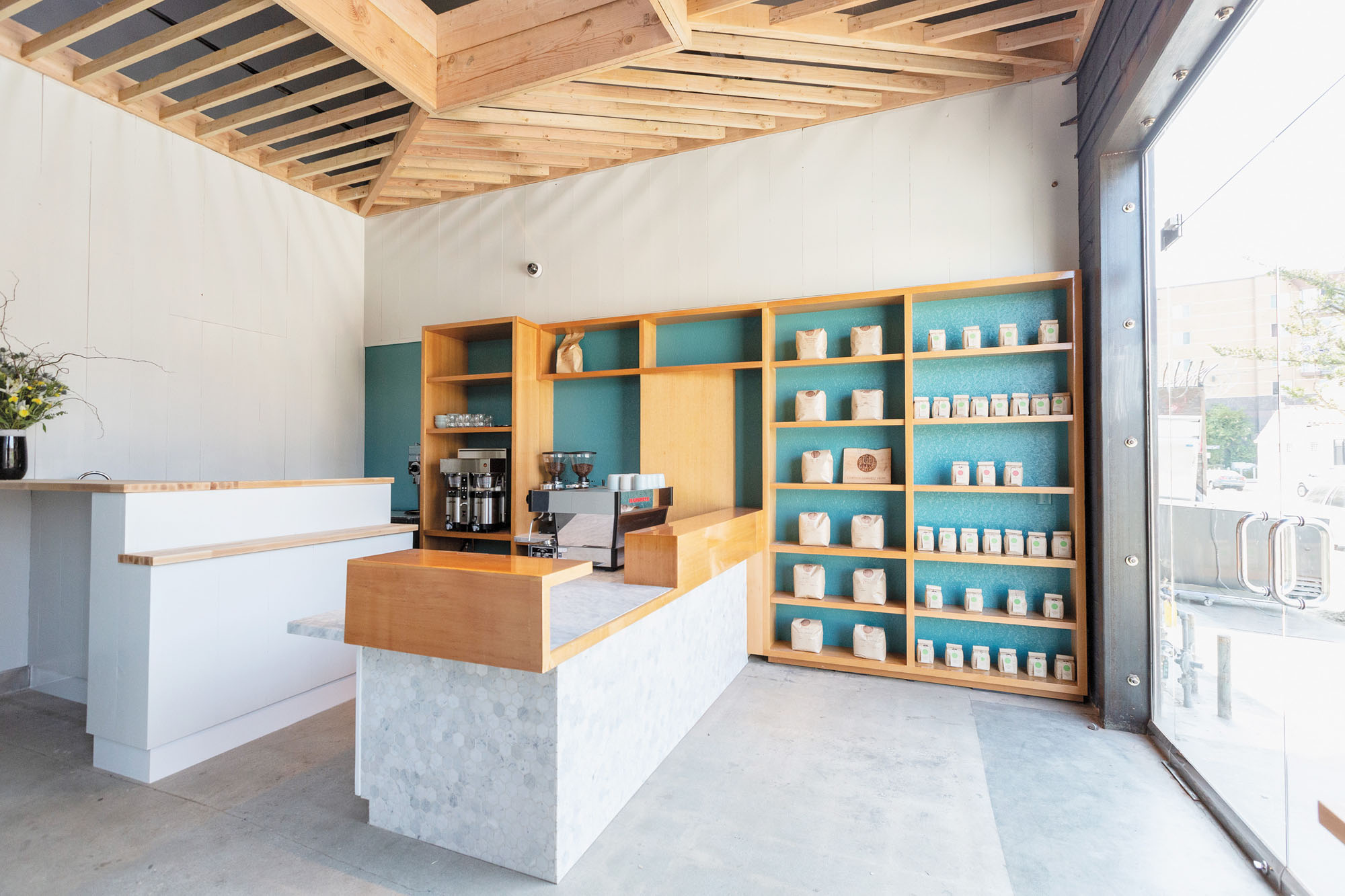 A photograph of the interior of a coffee shop with a tile bar and wooden built-in shelving