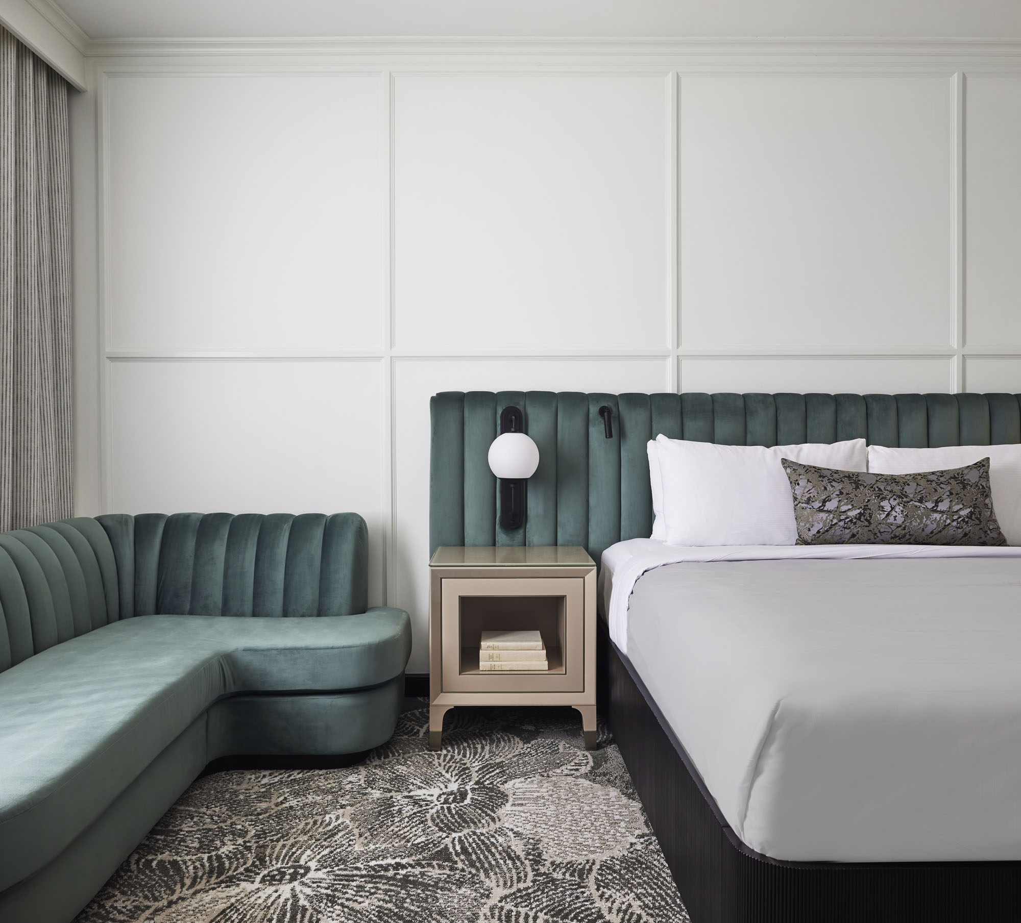 interior image of a hotel guest room with a bed and a teal couch
