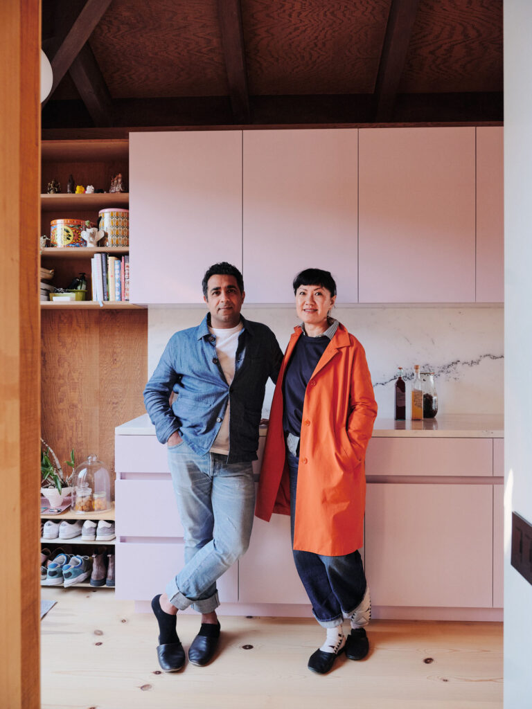 two people standing in a kitchen with pink cabinets