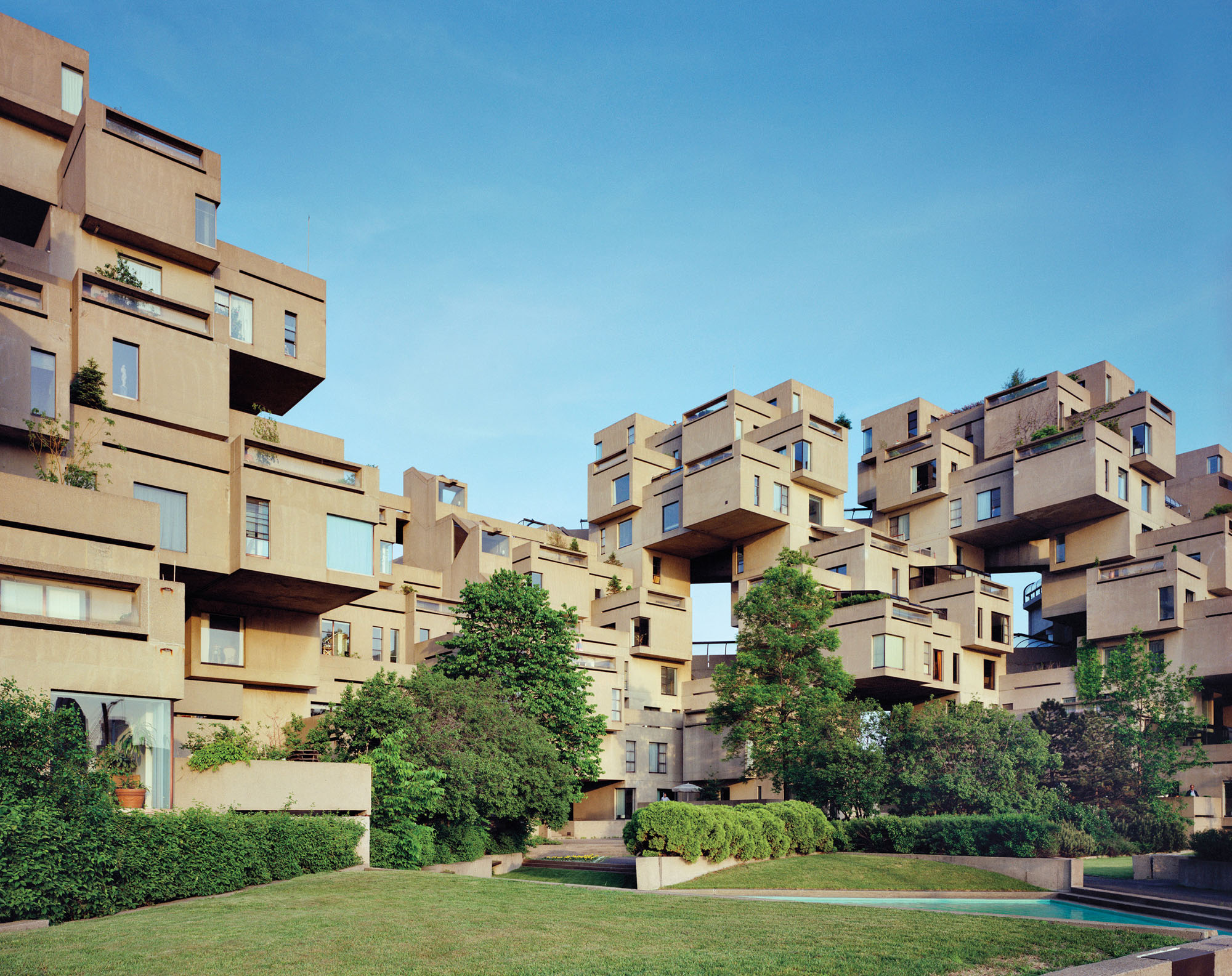 An exterior photograph of Habitat 67 in Montreal, stacks of beige boxes and abundant plantings.