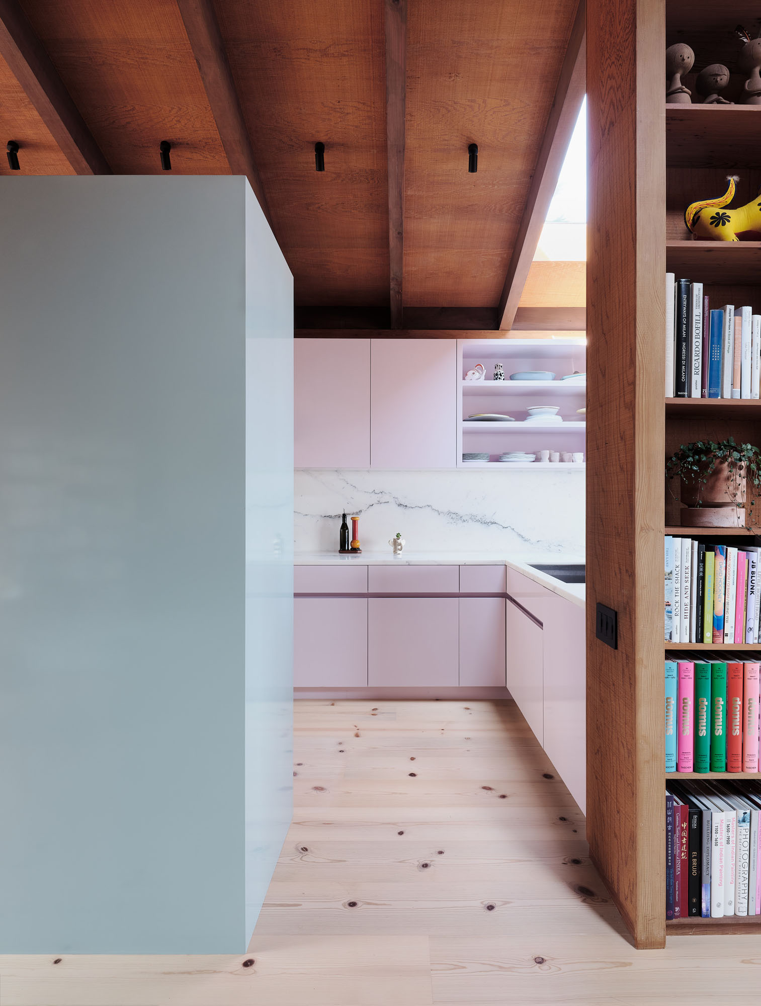 image of a kitchen with pastel cabinetry, light wood floors, and dark wood ceilings