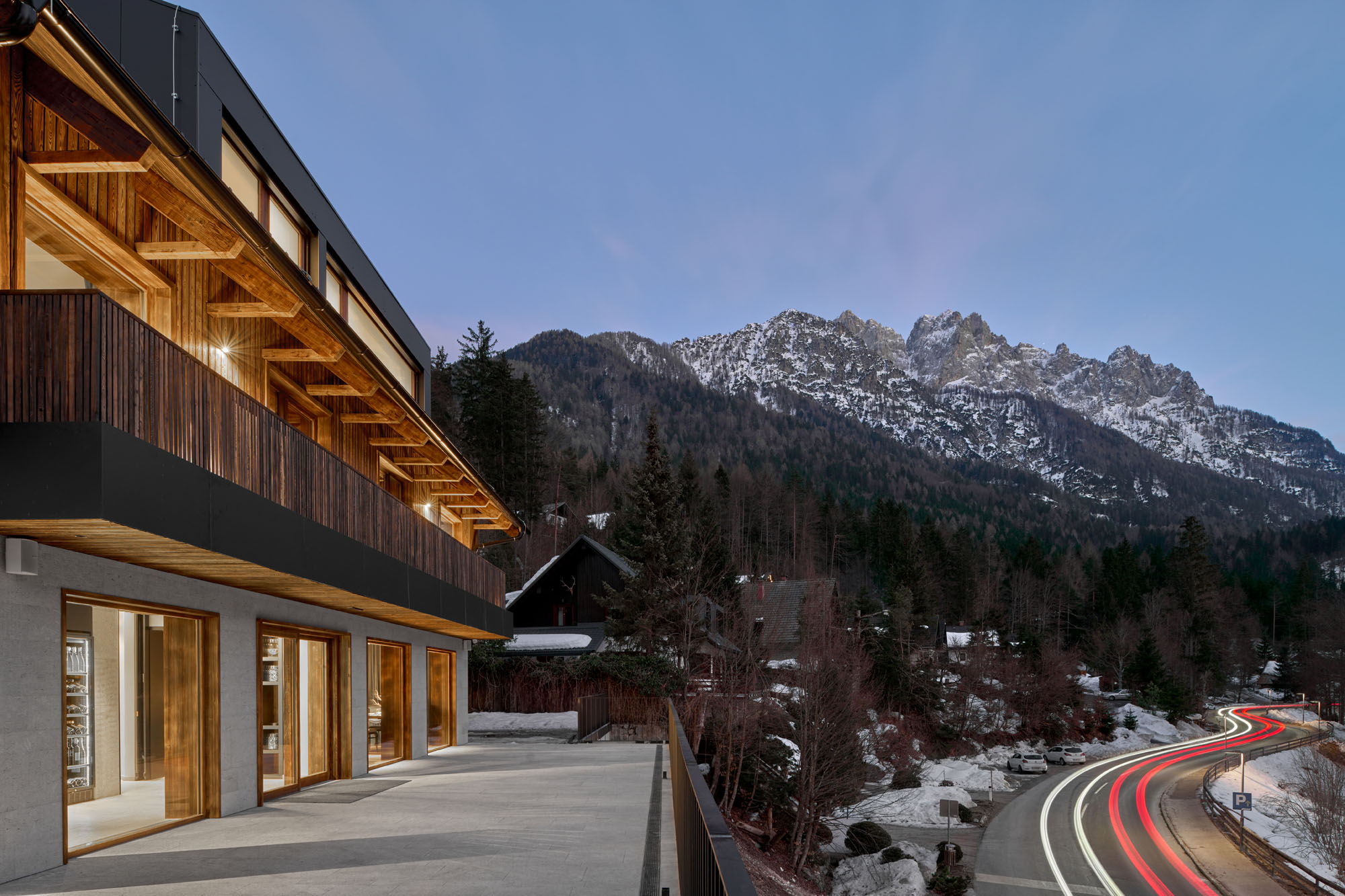 a photograph of the exterior of a hotel by a mountain and a highway