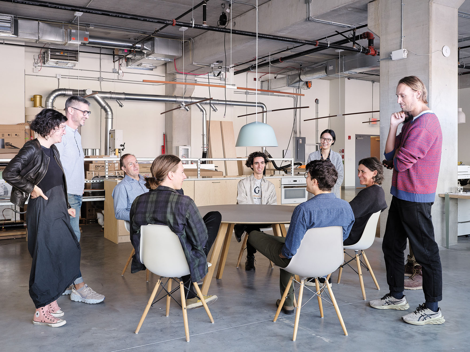 A photograph of a group of architects sitting around a table in their new office