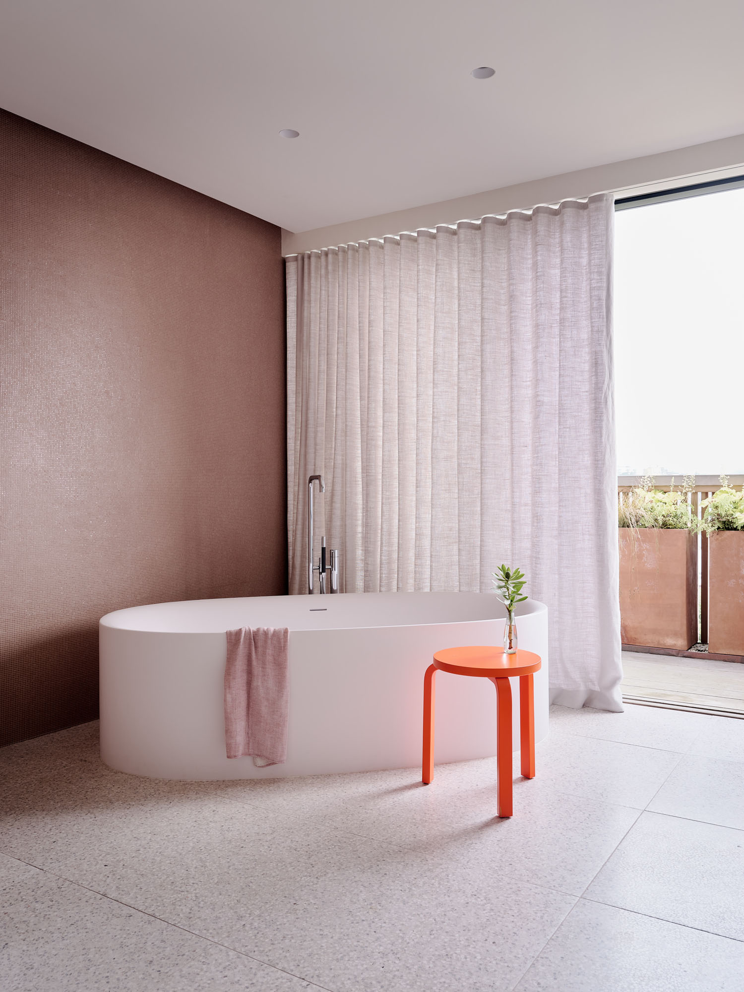 image showing a large round bathtub in a bathroom with a glass wall window
