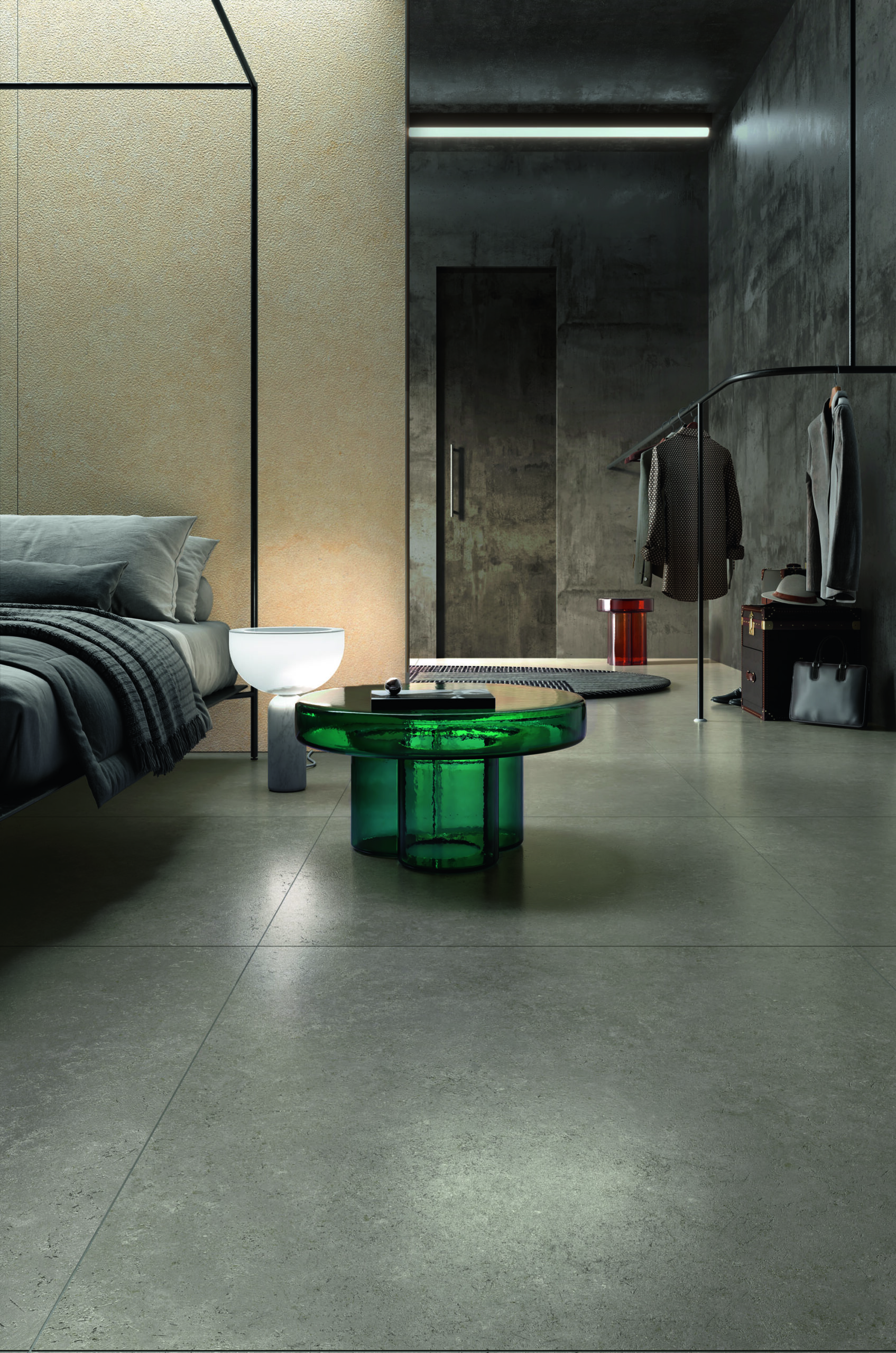 Bedroom with green glass table, hanging clothes and walls and floor covered in greenish porcelain tile.