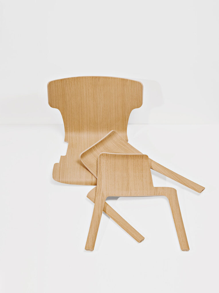 a disassembled plywood chair in three pieces