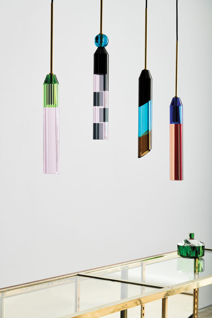 A photograph of four glass pendant lamps in a variety of colors