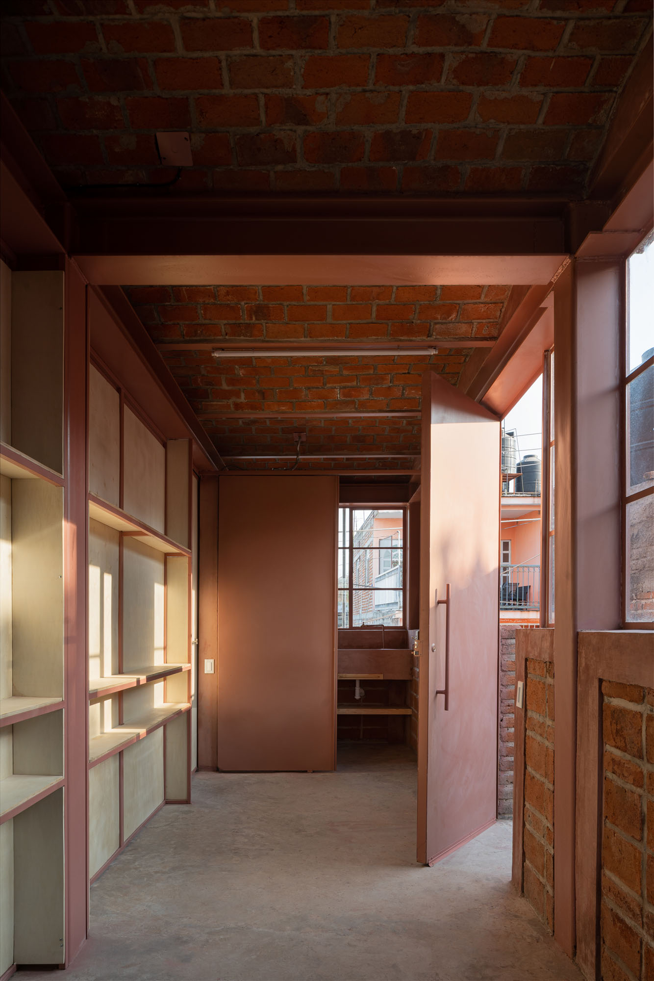 interior of a brick building with built in shelving and a door opening up onto a terrace 