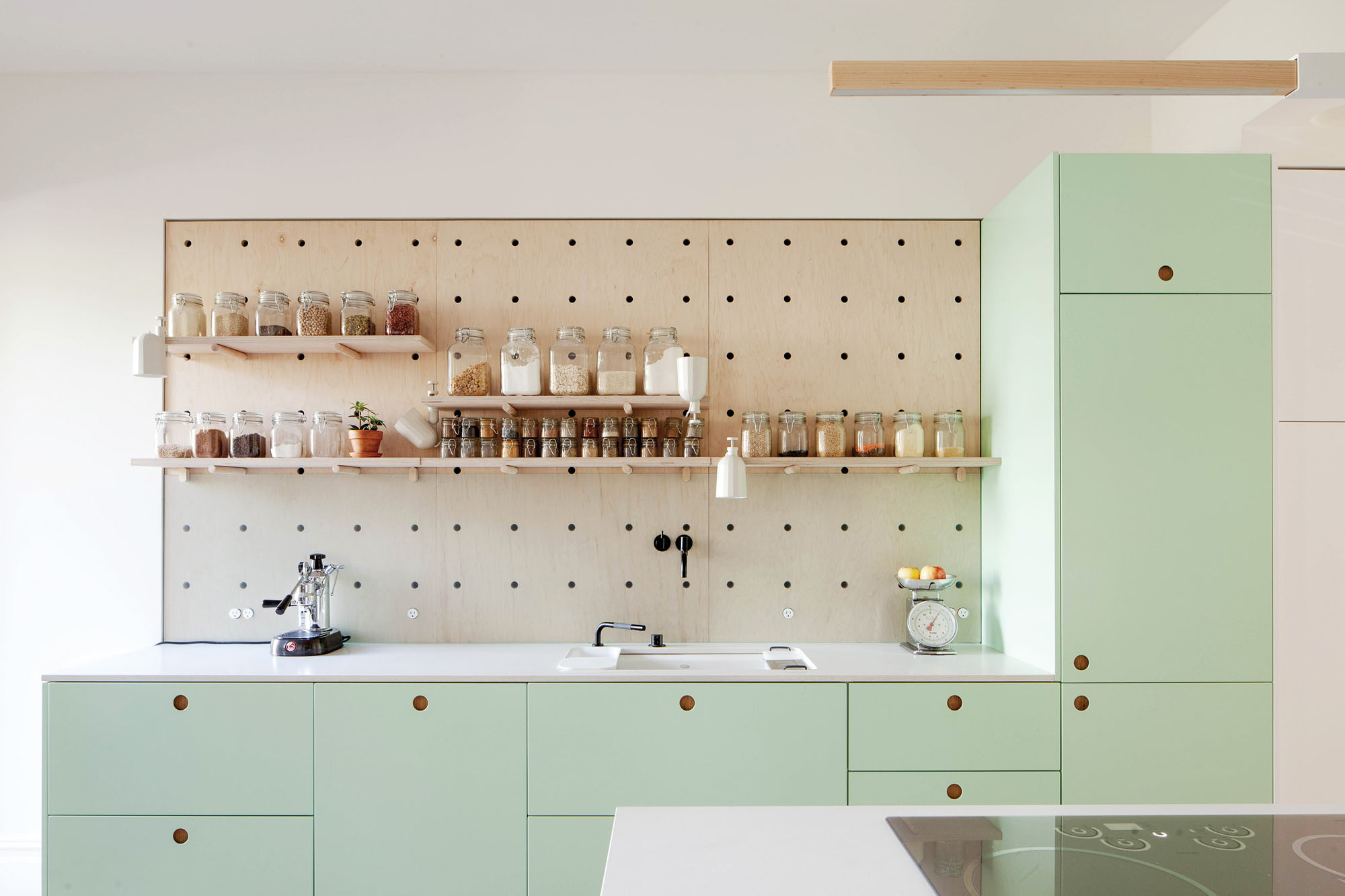A photograph of a kitchen with pistachio green cabinets