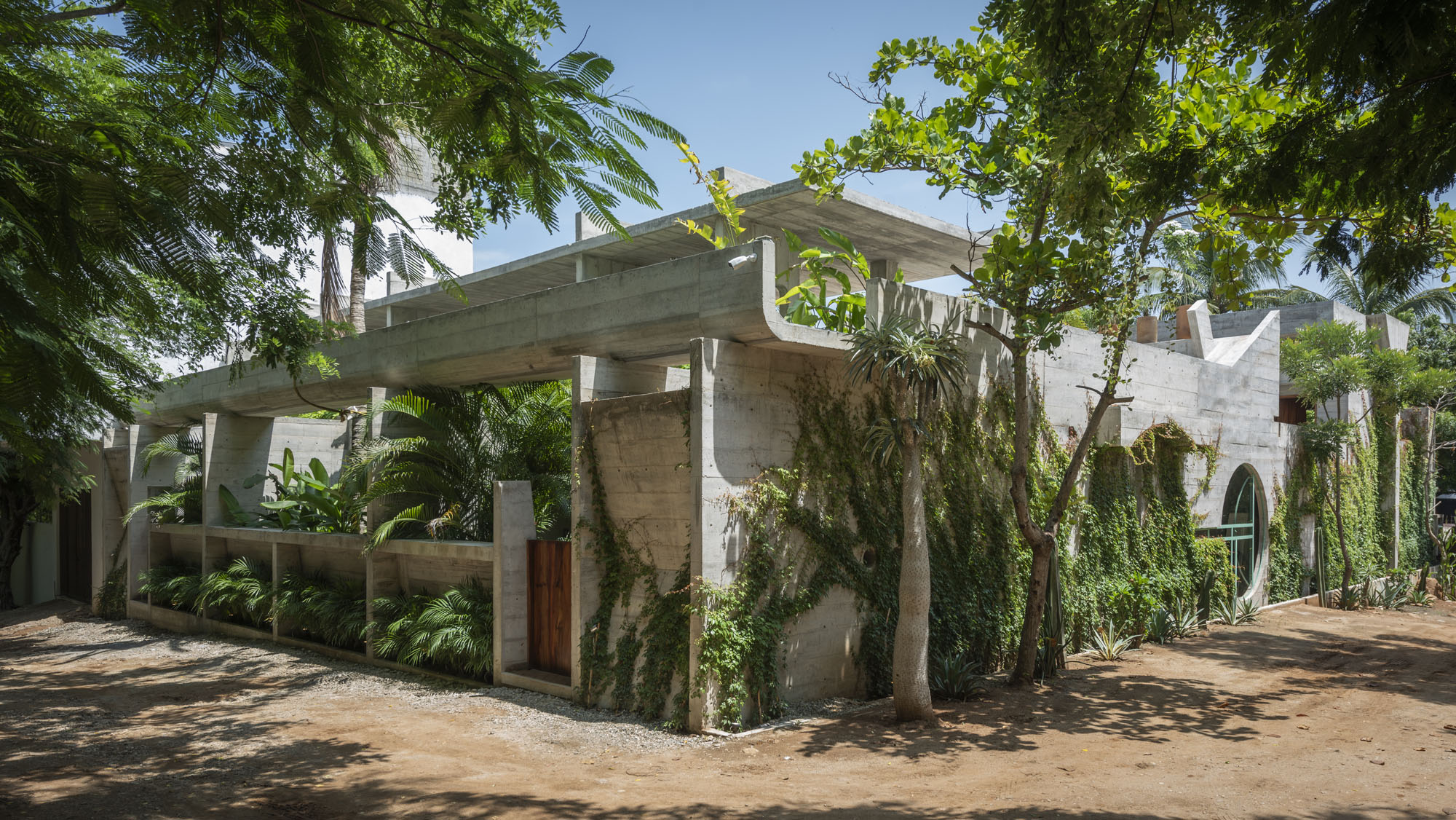 Exterior view of a concrete building nestled among lush tropical foliage