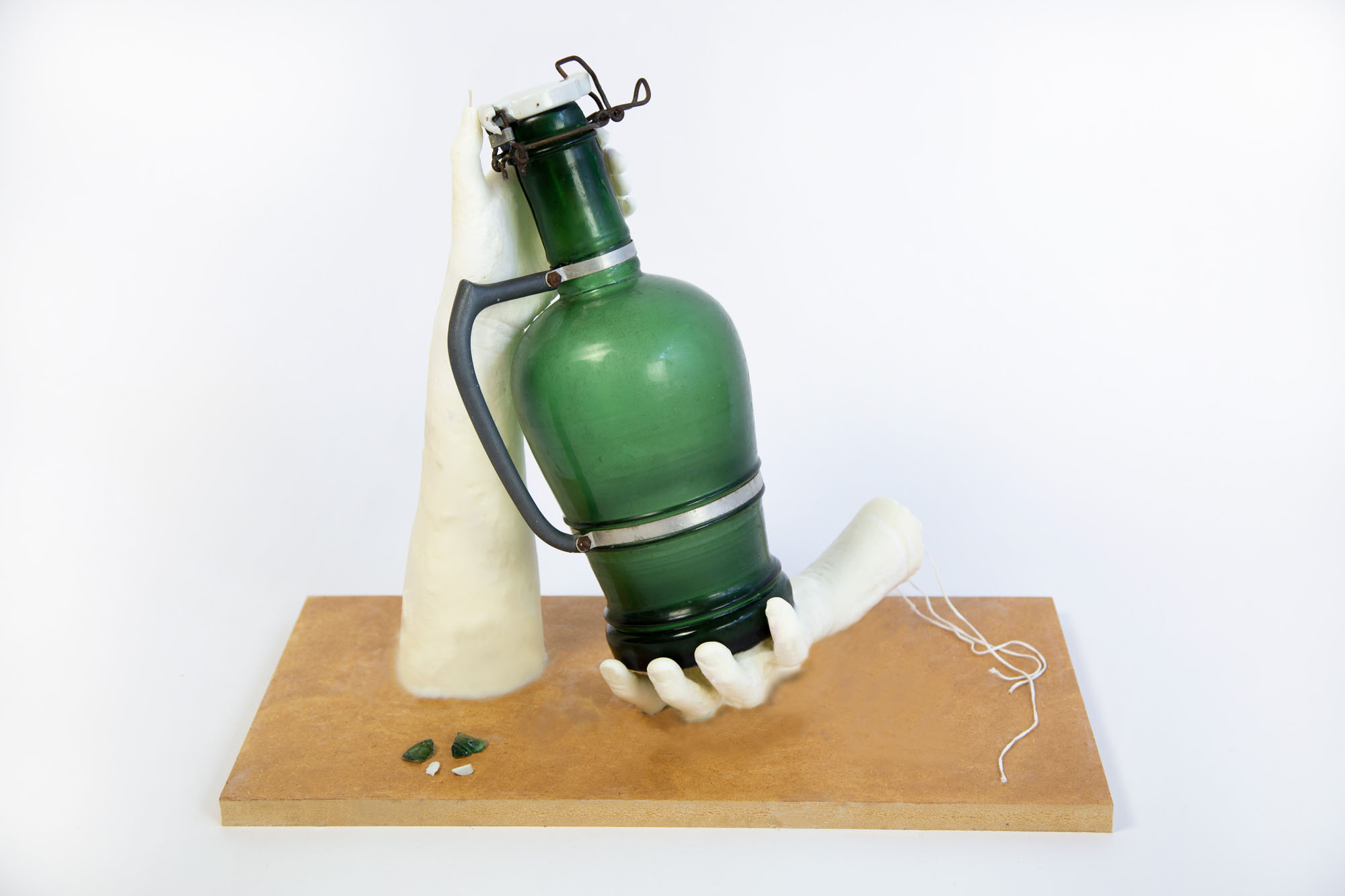 an image of a vintage glass bottle being held by two soy cast hands on a board 