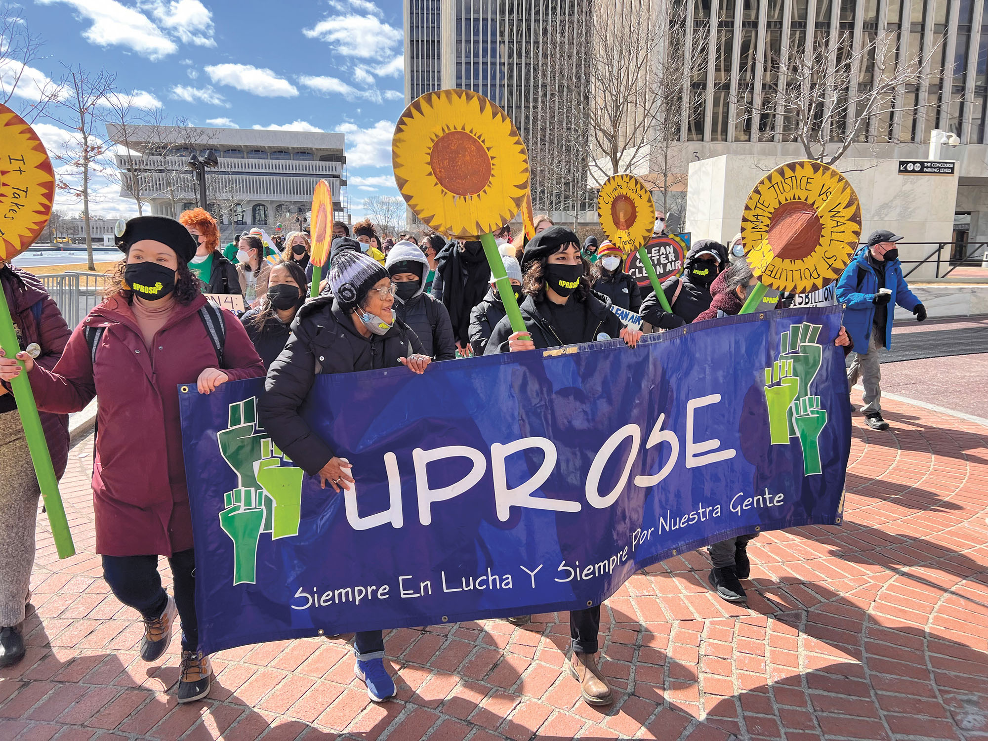 Climate justice protesters carrying a sign that reads "Uprose," a group that fights for community solar energy