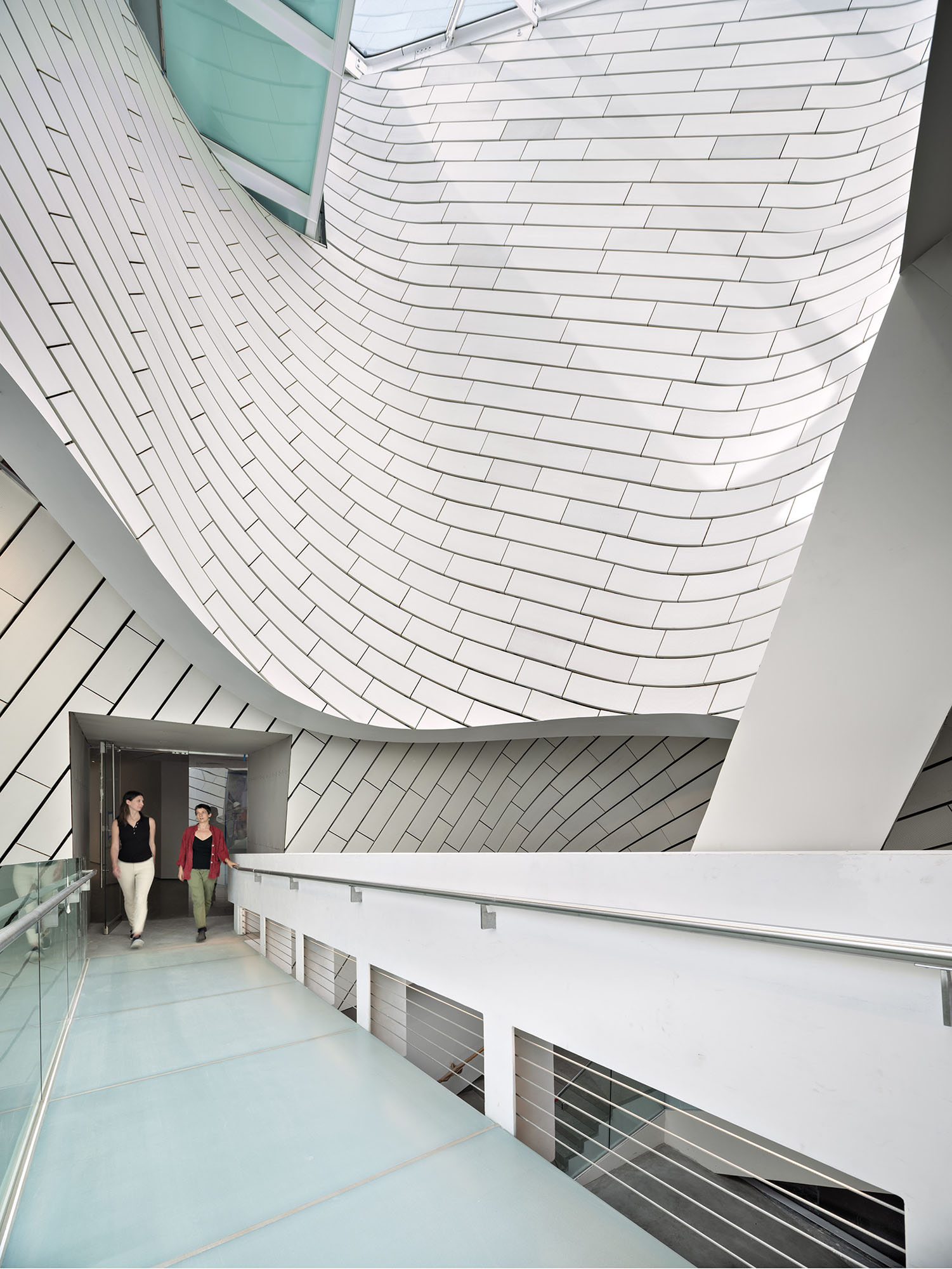 A view of the bridge across the atrium with white tile-clad walls