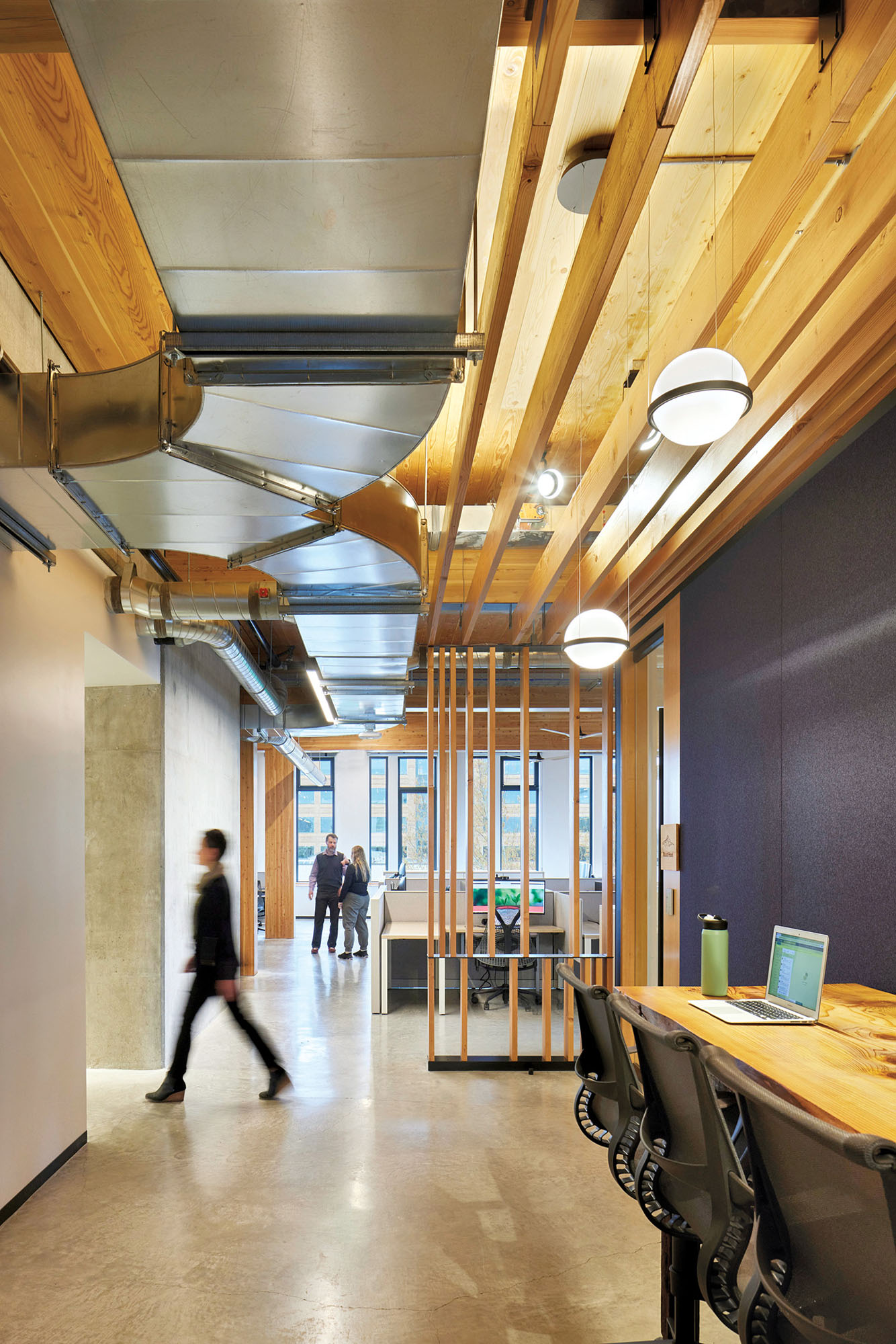 Detail photograph of a hallway in the PAE living building, its ceiling features wood details and the floor is polished concrete. 
