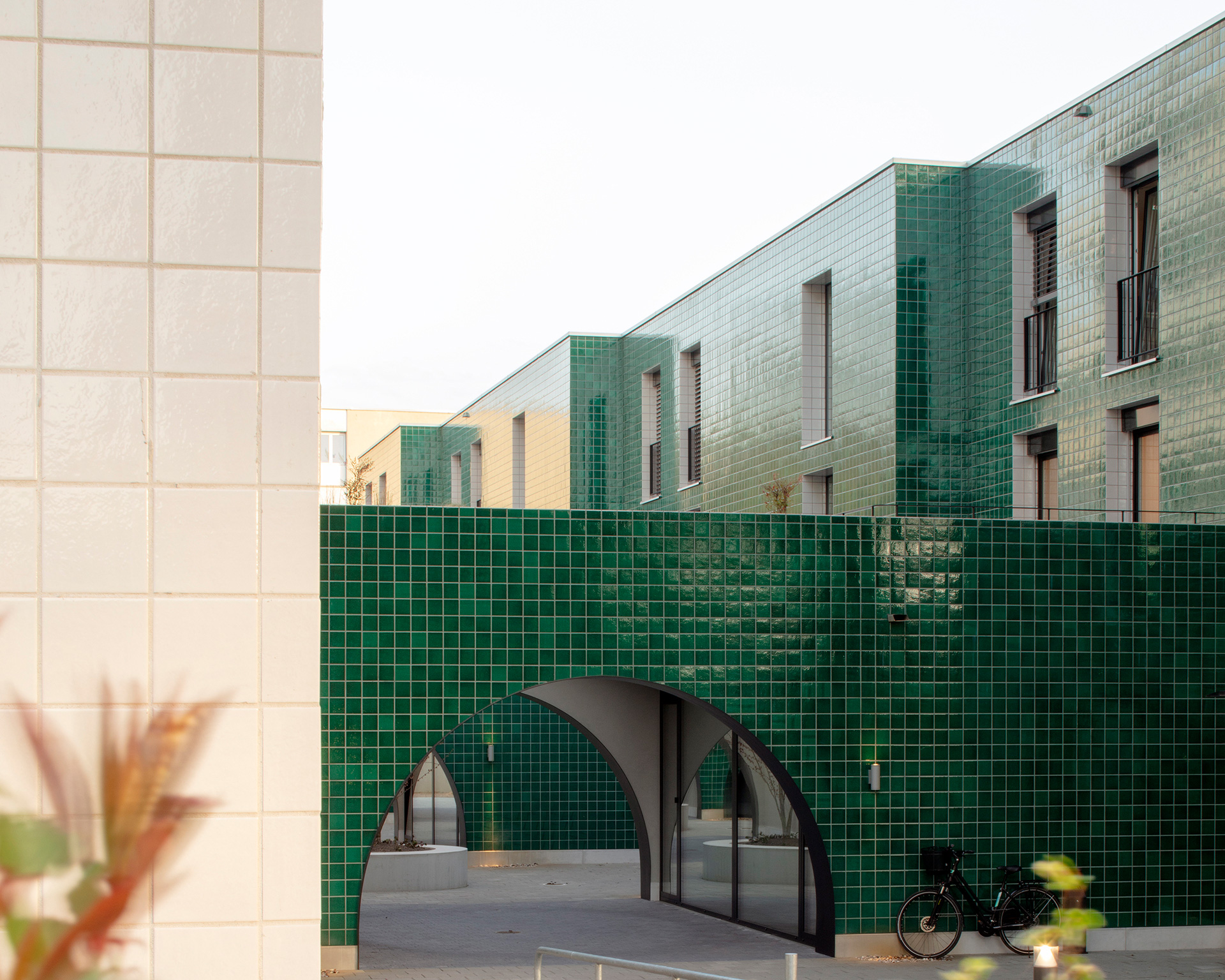 green tile clad building with an arched entryway