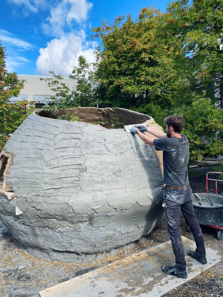man building a sphere of earthen material