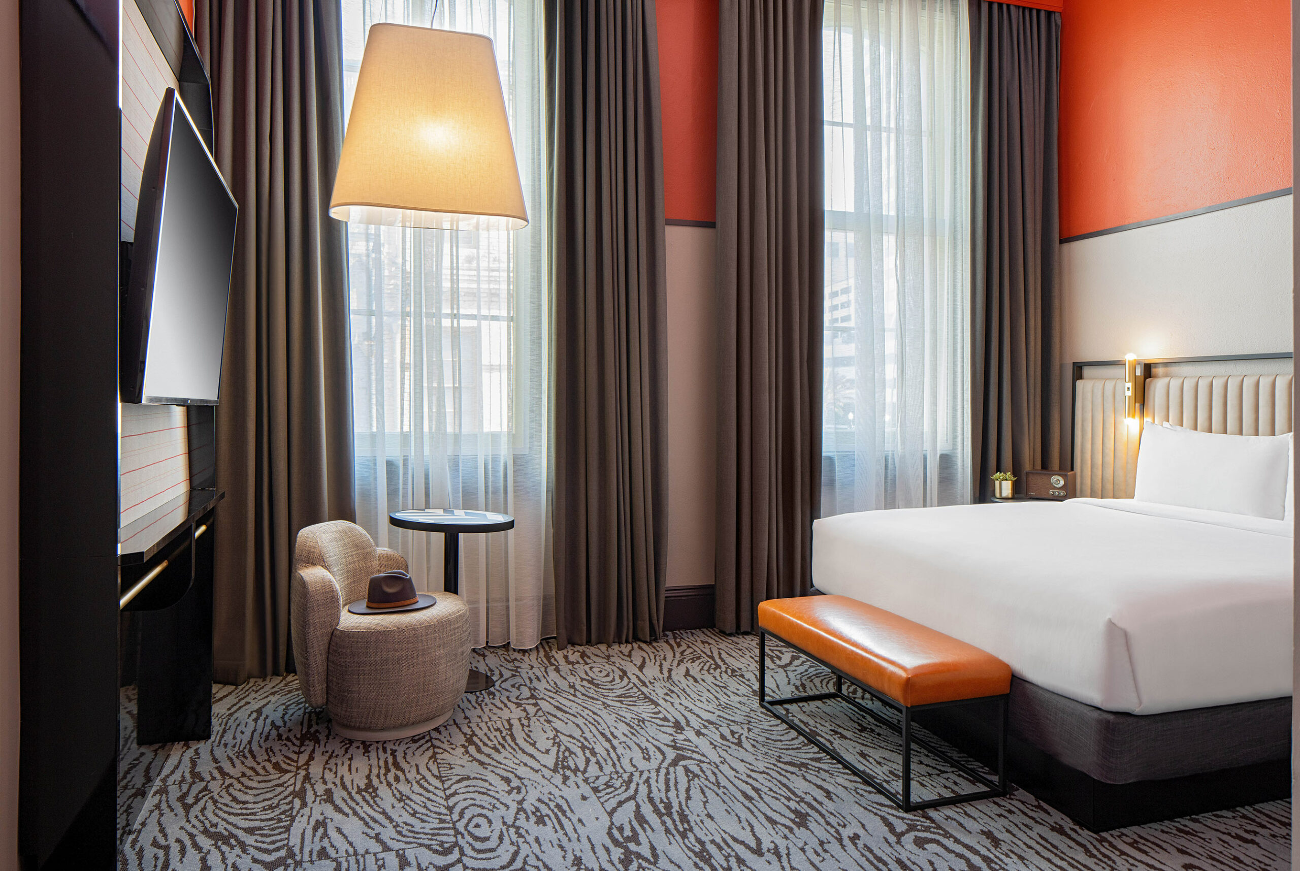 interior image of a hotel guest room with orange and white walls with grey curtains 