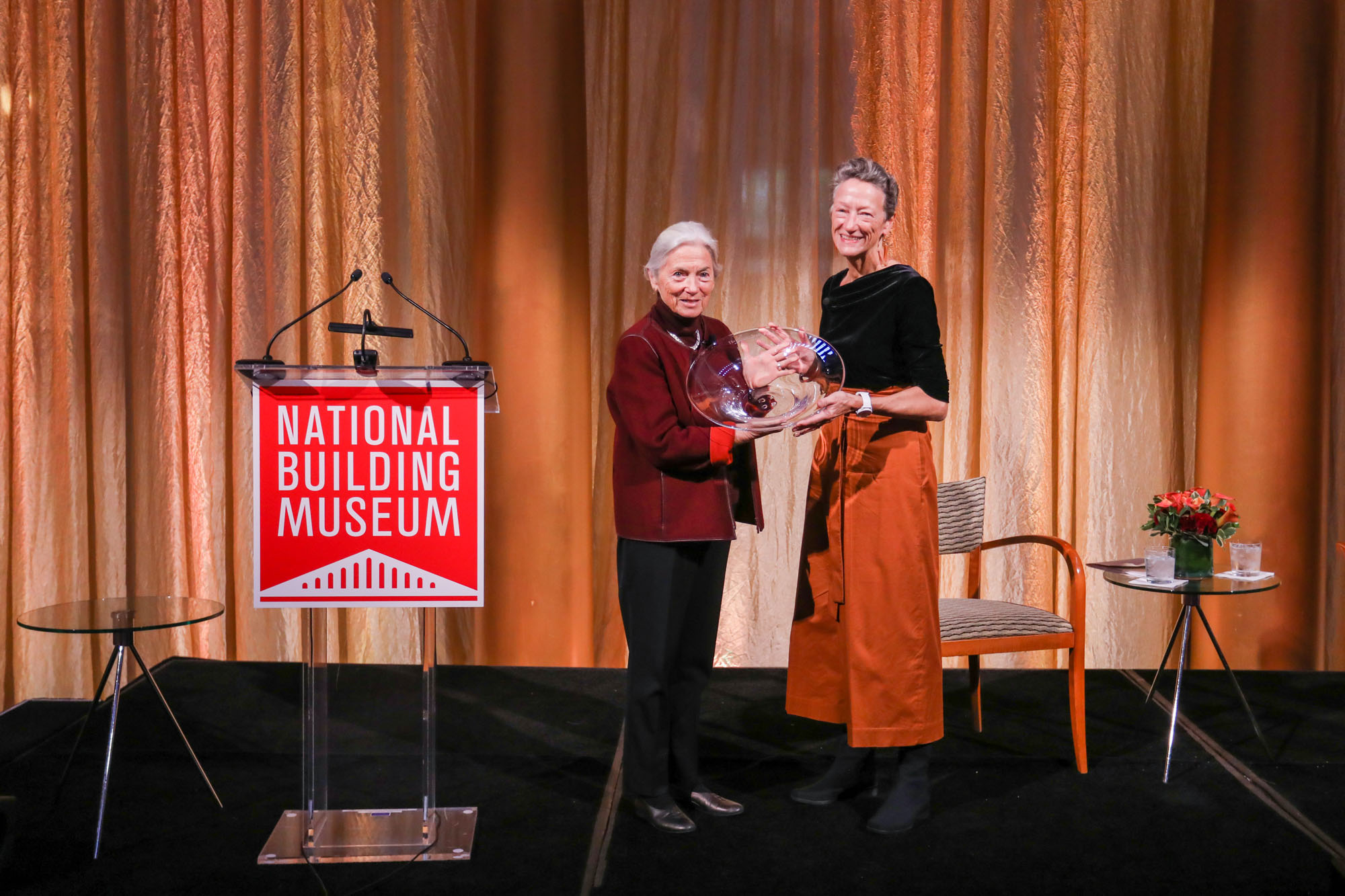 image of two people standing on a stage next to a podium that says "National building musuem"