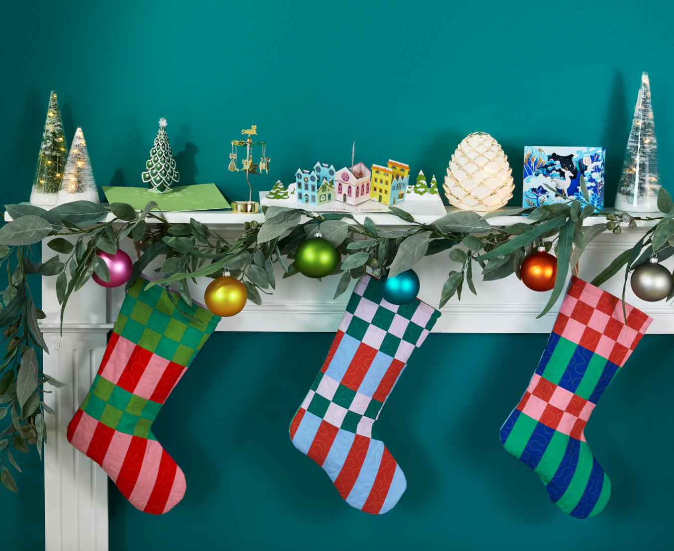 three quilted christmas stockings hanging on a mantle